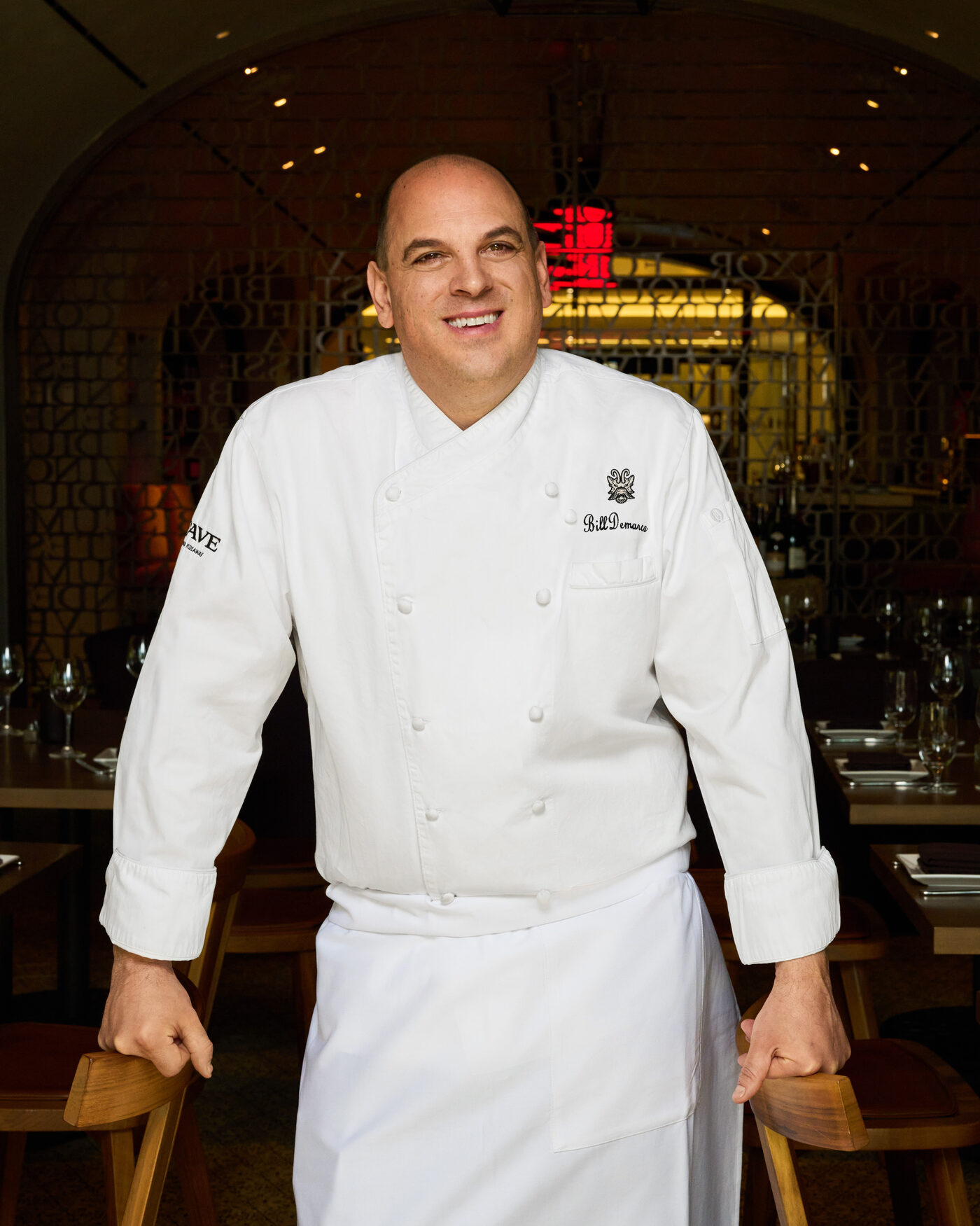 Executive Chef William DeMarco in chef's whites standing in La Cave's dining room