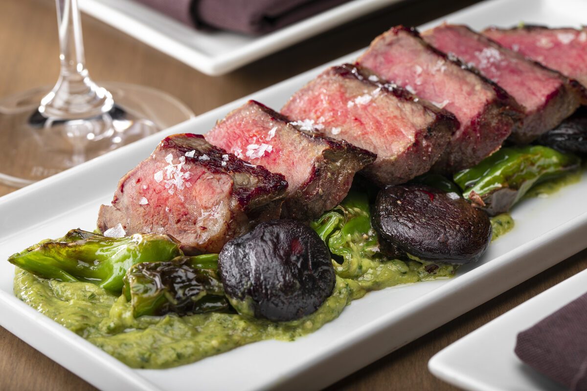 Sliced medium-rare sirloin with blistered shishitos and salsa verde
